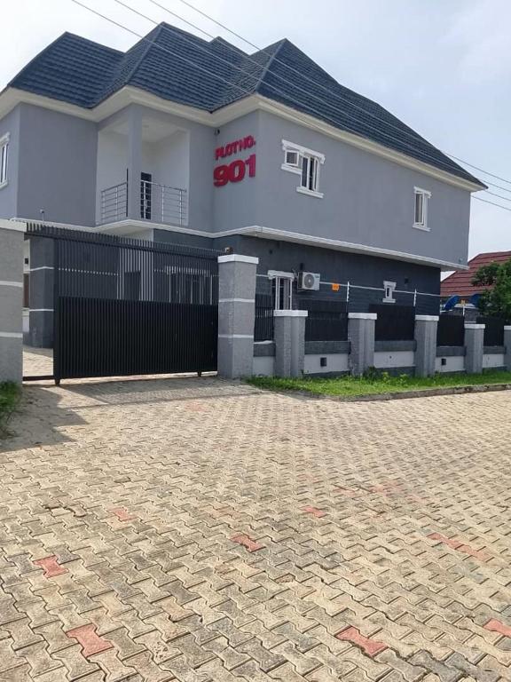 a white house with a black gate and a building at Lynstel Apartment & Suites in Abuja