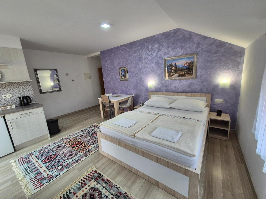 a bedroom with a large bed with a purple wall at Apartments City Paradise in Mostar
