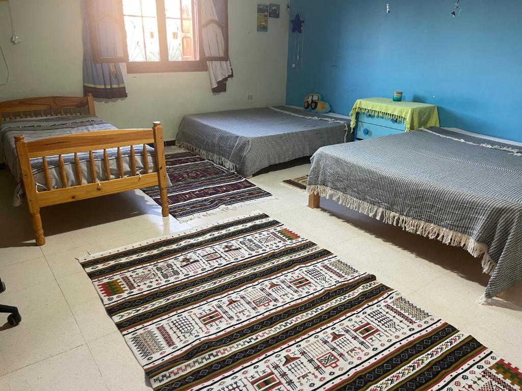 a room with three beds and rugs on the floor at Adam House in Ghardaïa
