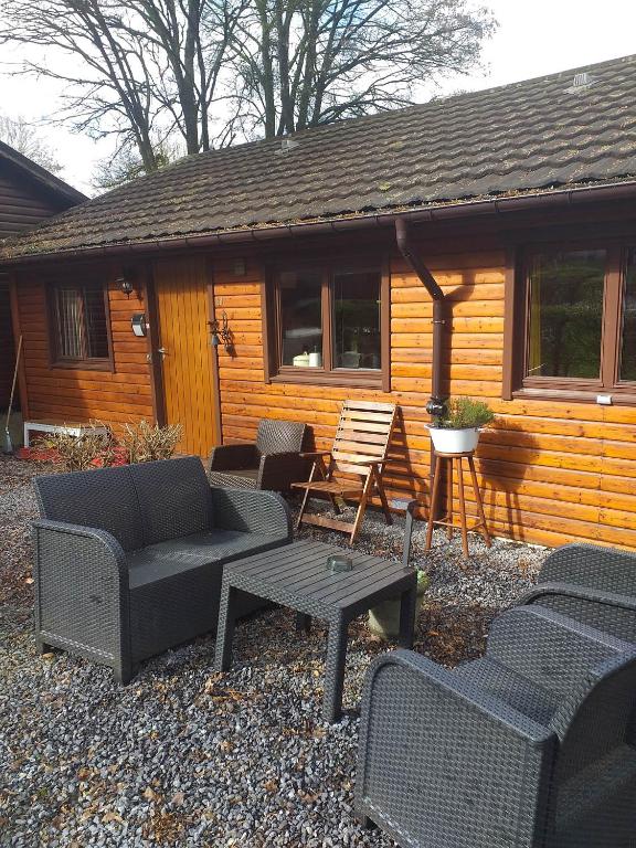 a group of chairs and tables in front of a cabin at Vakantiehuis Malaika in Rendeux