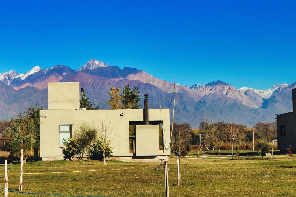a house in a field with mountains in the background at Complejo Piuquenes Valle de Uco in Vista Flores