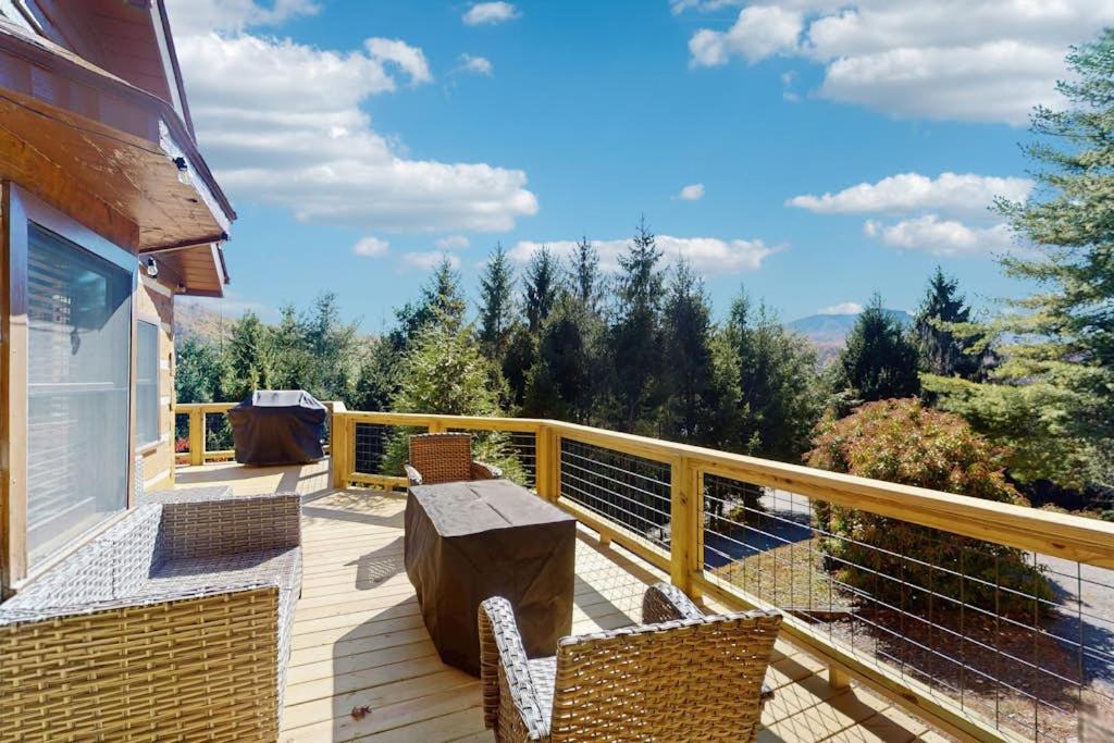 a deck with a table and chairs on a balcony at Napping Bear Cabin in Banner Elk