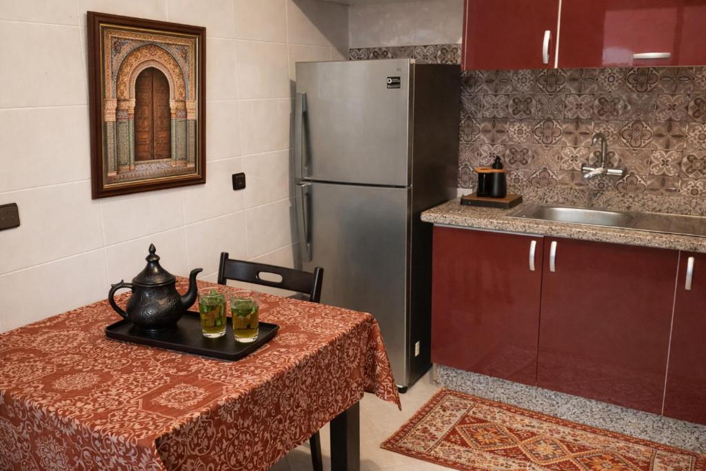 a kitchen with a table and a refrigerator at Appartement moderne à 5 min de la plage de Mehdia Vacances idéales 2026 in Mehdiya-Plage