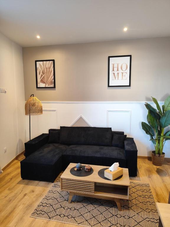 a living room with a black couch and a table at Jardin De La Sagesse in Sotteville-lès-Rouen