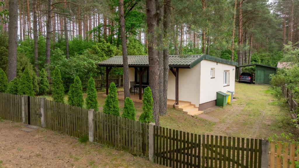 a small house in the woods with a fence at Domek w Puszczy in Wiartel