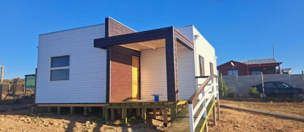 a tiny house with a wooden porch on a field at CABAÑA CON TINAJa in Guanaqueros