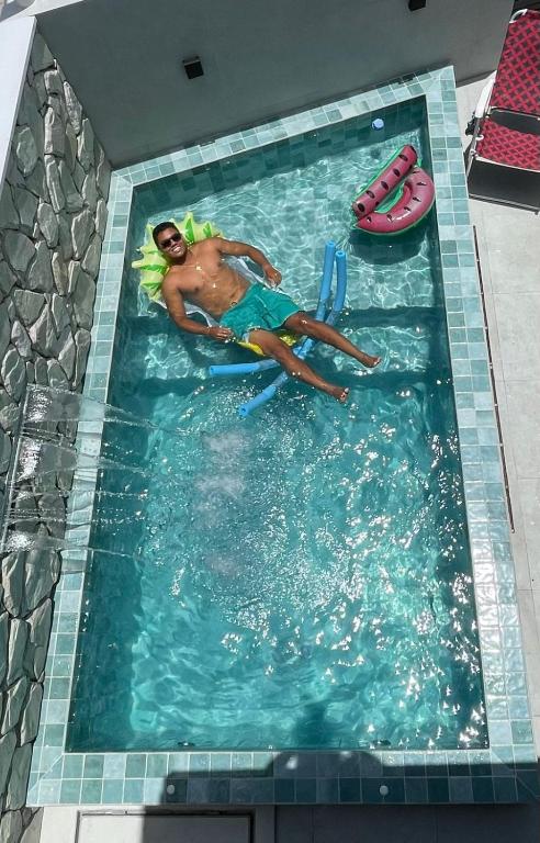 a person in a swimming pool in a swimming pool at Casa06Frances com decoração moderna à 8min de carro da praia do frances com piscina PRIVATIVA, 03 quartos com AR in Marechal Deodoro