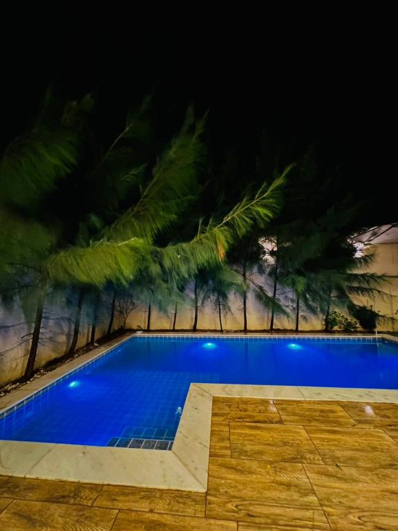 a swimming pool at night with trees in the background at Casa Temporada Trairi in Trairi