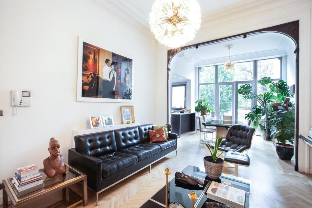 a living room with a black leather couch at B&B Quatre20cinq in Antwerp