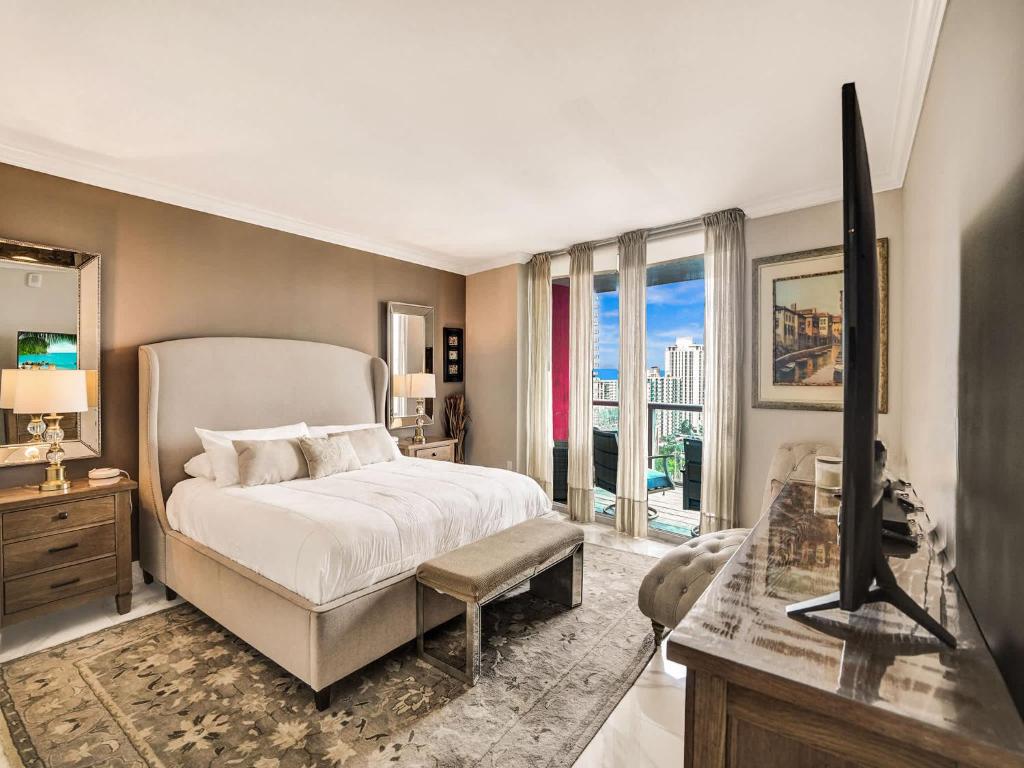 a bedroom with a bed and a tv and a window at Luxury 3BR Water view 18th-Floor Deck Pool in Hallandale Beach