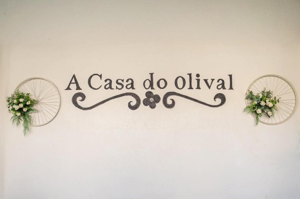 a casa do oliva sign on a wall with flowers at A Casa do Olival in Mealhada