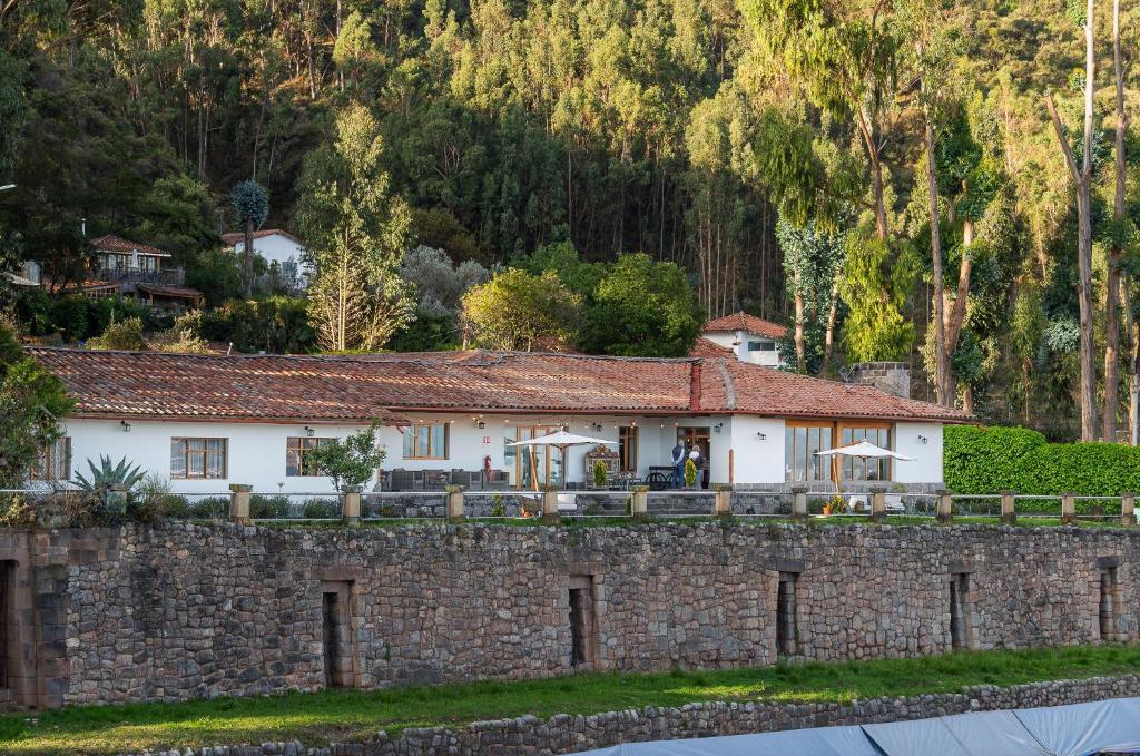 a house behind a stone wall next to a mountain at Palacio Manco Capac by Ananay Hotels in Cusco