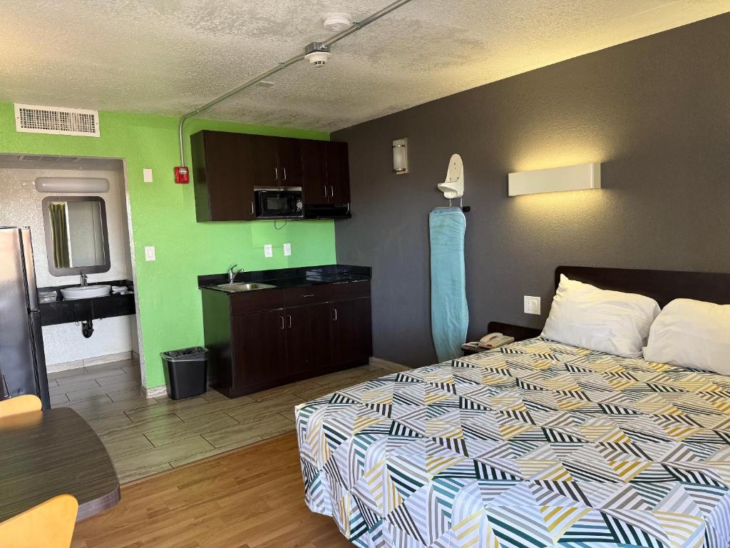 a bedroom with a bed and a kitchen with green walls at Motel 6-Barstow, CA in Barstow