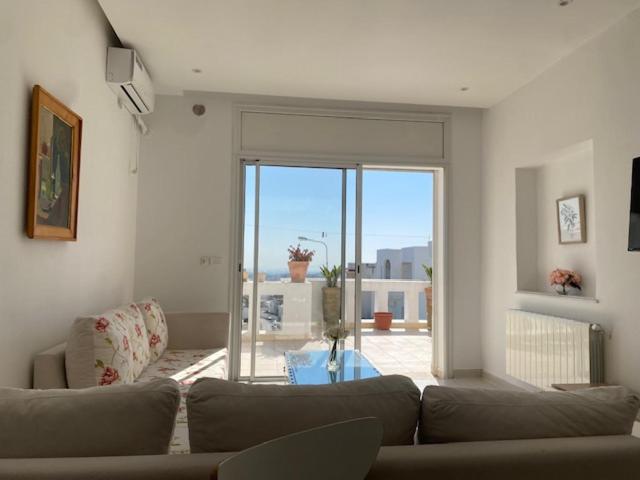 a living room with a couch and a large window at Panoramic 2 bedrooms Ennassr in Ariana