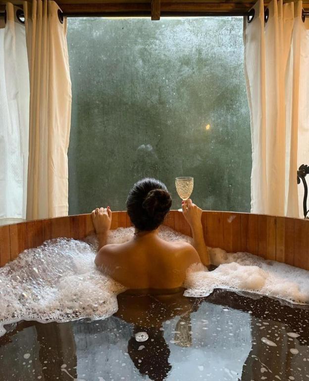 a man in a bath tub with a glass of wine at Cabanas do Rio in Alfredo Wagner