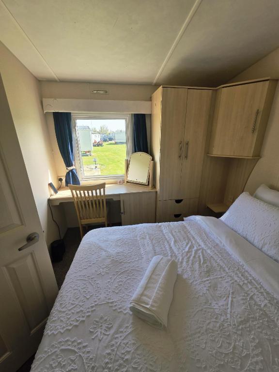 a bedroom with a bed and a desk and a window at Loulex Deluxe in Jaywick Sands