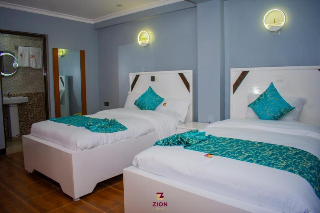 two beds in a room with blue walls at Zion Hotel in Nakuru