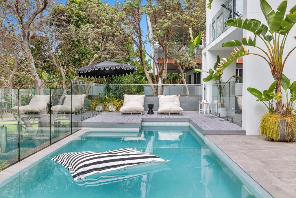a swimming pool with two chairs next to a house at Luxe on North Point in Kingscliff