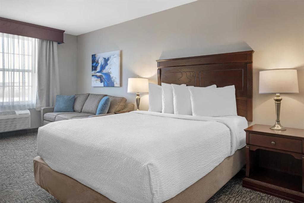 a hotel room with a large bed and a couch at Best Western Plus Grand-Sault Hotel & Suites in Grand Falls