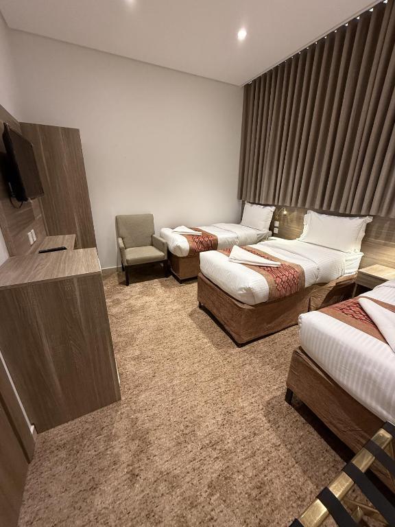 a hotel room with two beds and a chair at Retaj Al Noor Hotel, فندق ريتاج النور in Medina
