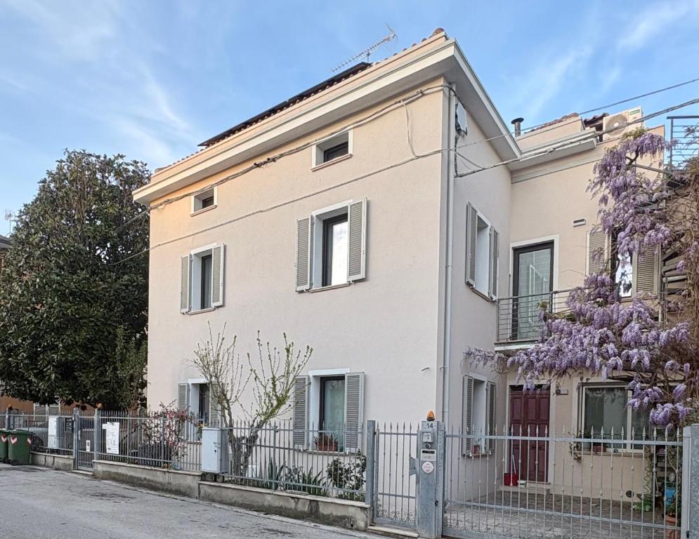 a white house with a fence and a flowering tree at B&B Glicine in Civitanova Marche