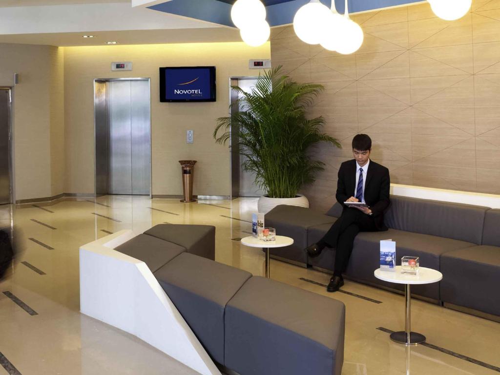 a man in a suit and tie sitting in a lobby at Shenzhen Novotel Watergate in Shenzhen