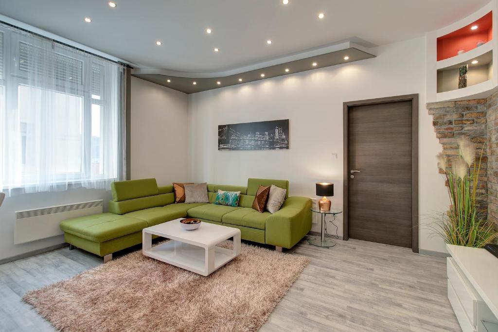ブダペストにあるTamara Apartmentのリビングルーム(緑のソファ2台、テーブル付)