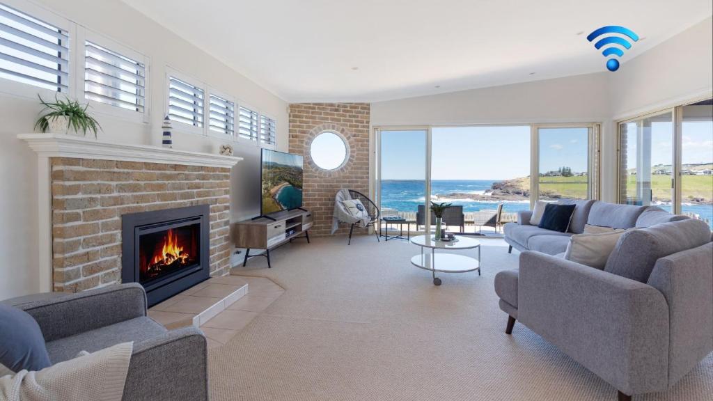 a living room with a fireplace and the ocean at Bombora at Kiama in Kiama