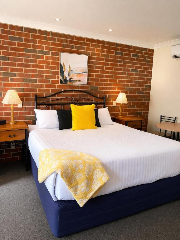 a bedroom with a large bed with a brick wall at Poachers Paradise in Rutherglen