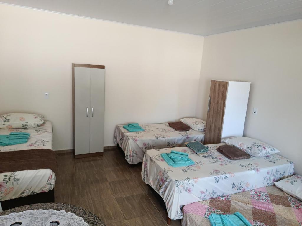 a room with three beds and a door to a bedroom at Pousada Paraíso in Telêmaco Borba