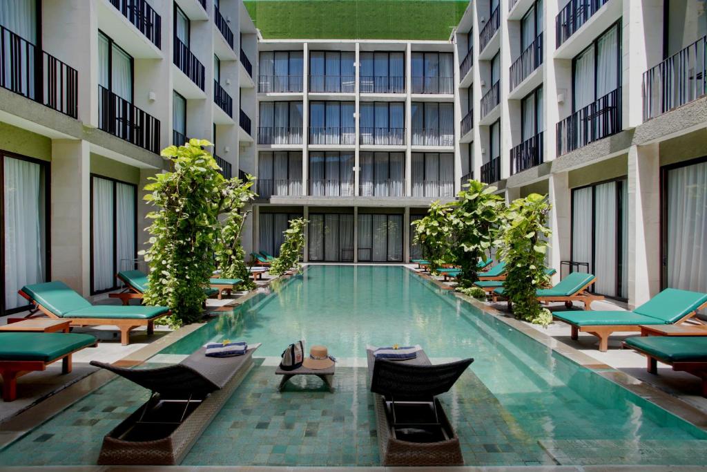 a large swimming pool in a building with lounge chairs at Hotel Terrace at Kuta in Legian