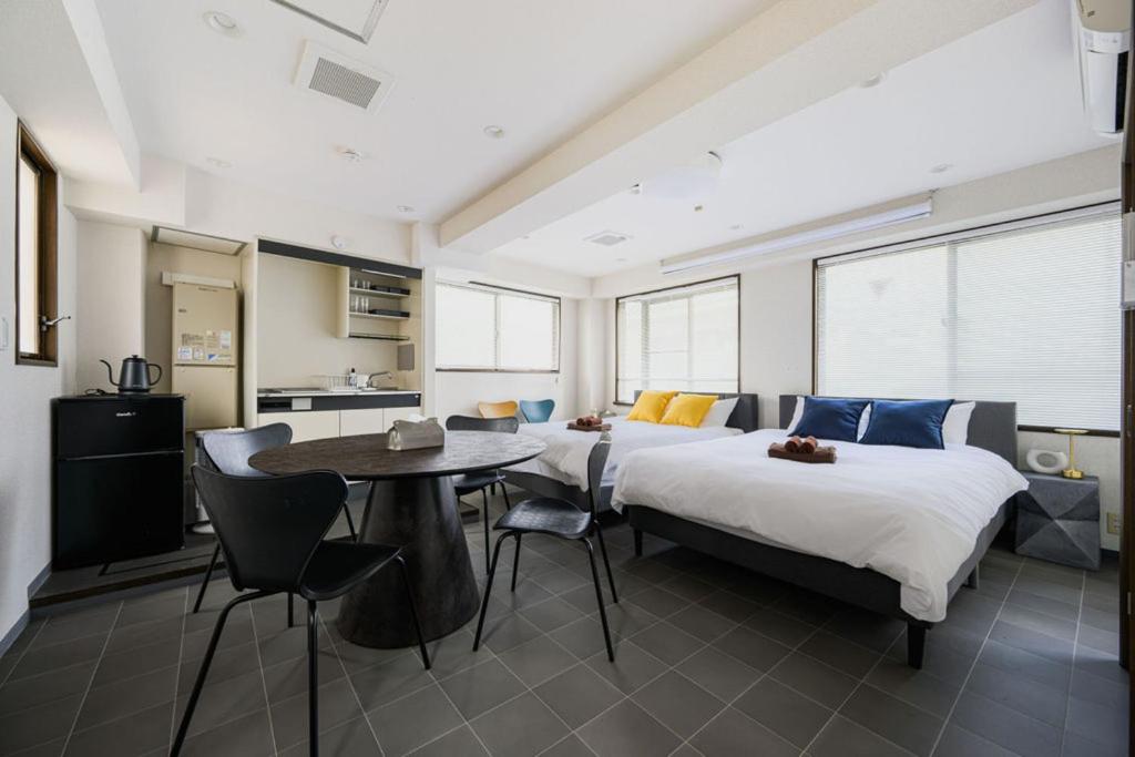 a bedroom with two beds and a table with chairs at メーイン北 in Tokyo