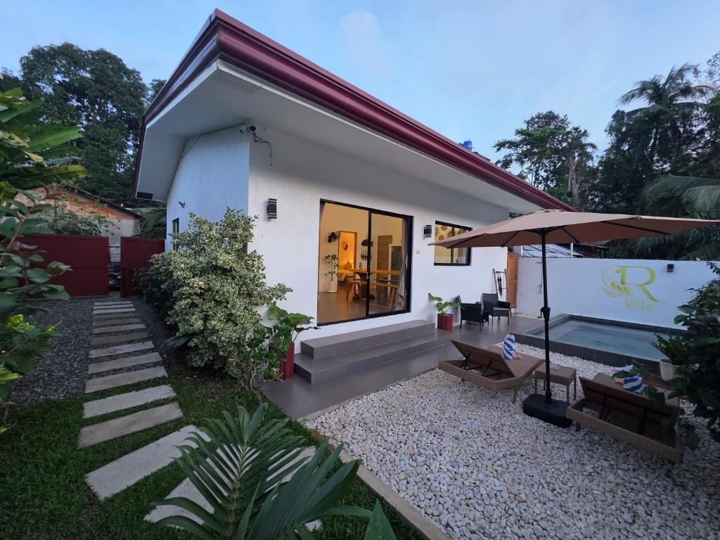 a small white house with a patio and an umbrella at RVilla El Nido in El Nido