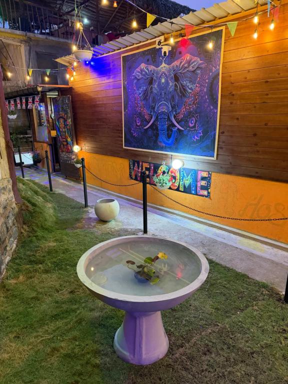a table in the grass with a painting on the wall at Okan Rock Hostel Ella in Ella