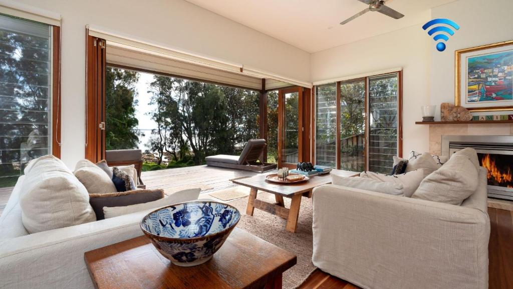 a living room with white furniture and a fireplace at Tula in Currarong