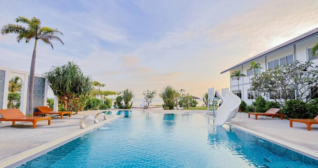 a pool at a resort with benches and a building at The Princess Beachfront Resort in Ban Tha Fat