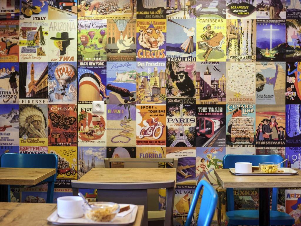 ein Restaurant mit zwei Tischen und einer mit Postern bedeckten Wand. in der Unterkunft hotelF1 Laval in Changé