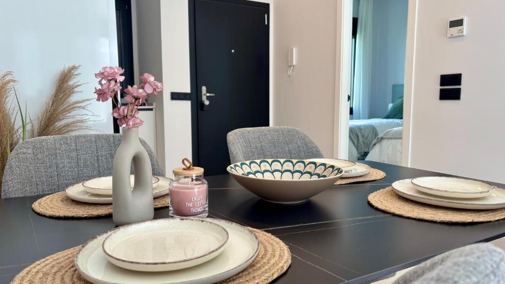a dining room table with plates and a vase with flowers at Atrio Homes Sansueña in Córdoba