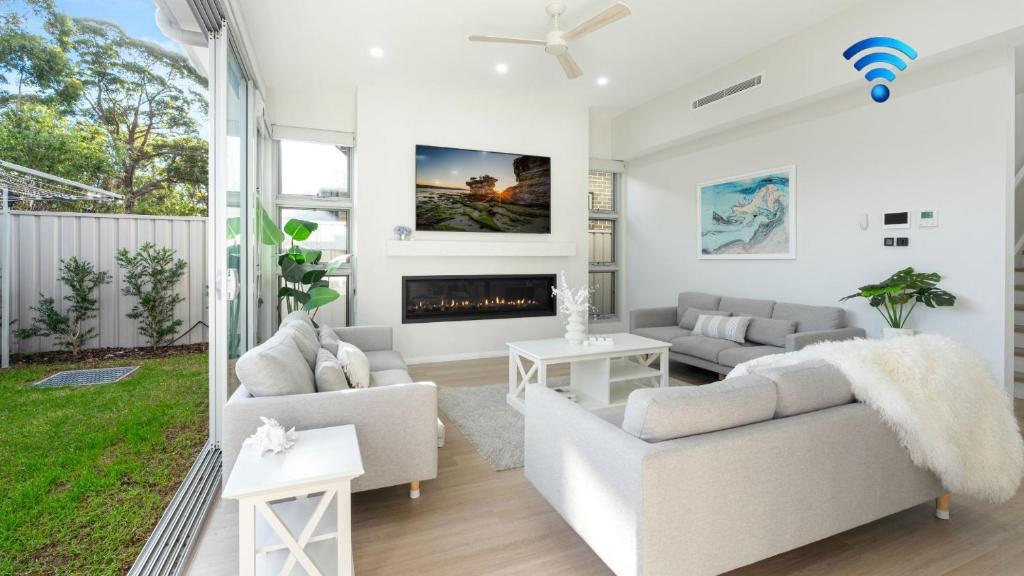 a living room with white furniture and a fireplace at Elliniko in Callala Beach