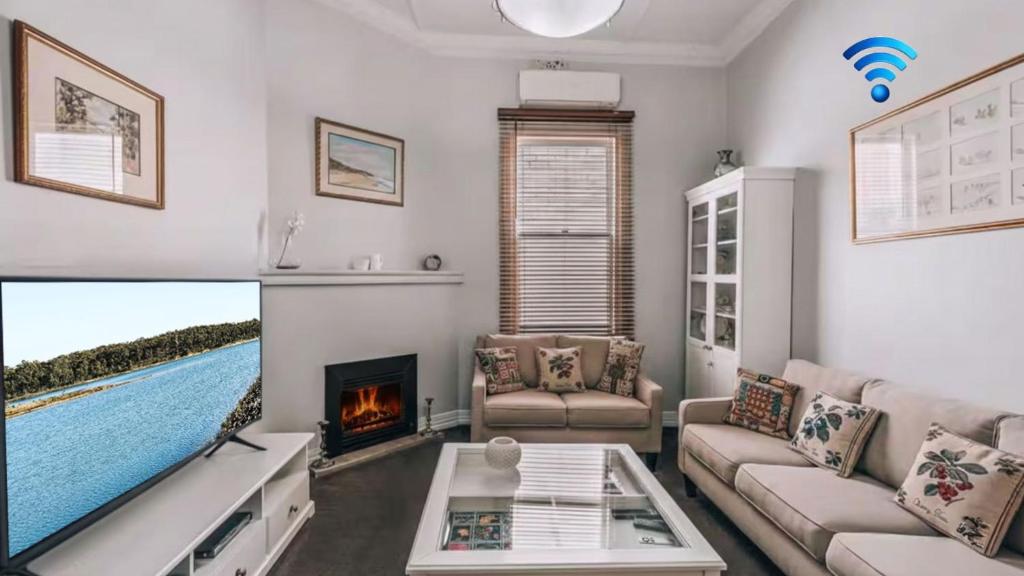 a living room with a large tv and a fireplace at Family Cottage in Bendigo