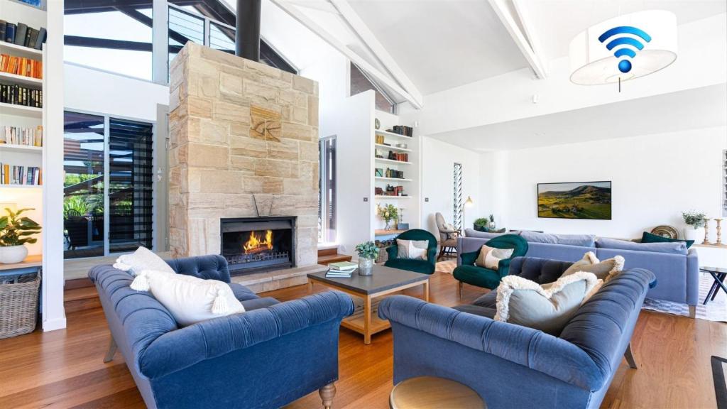 a living room with blue couches and a fireplace at Fletchers Lane Escape in Meroo