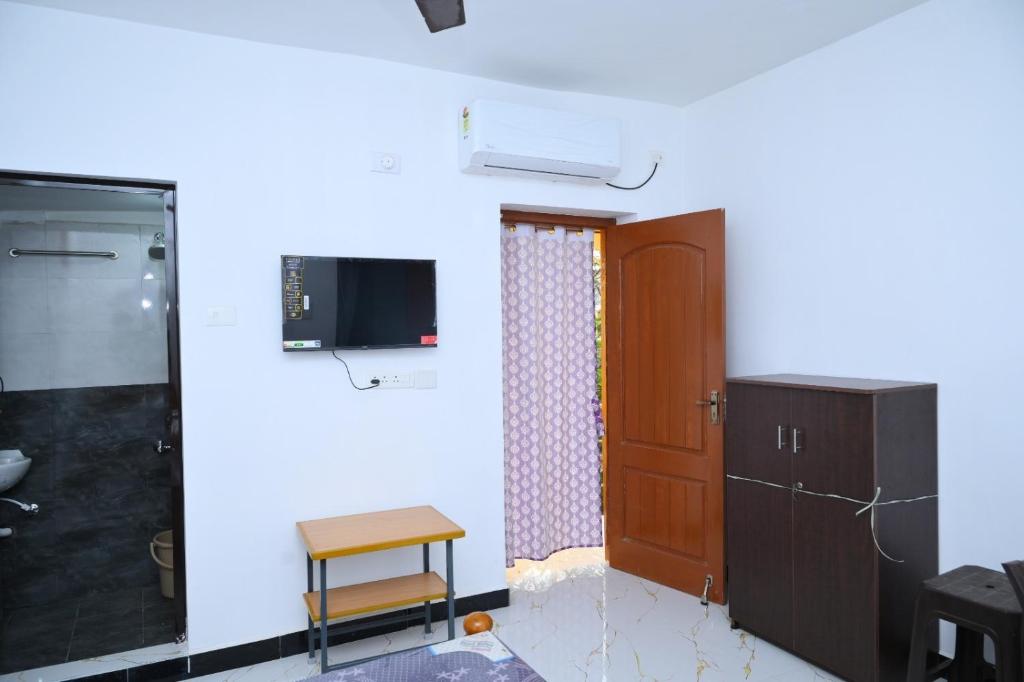 a room with a door and a tv and a cabinet at Le Lagrave Inn in Pondicherry
