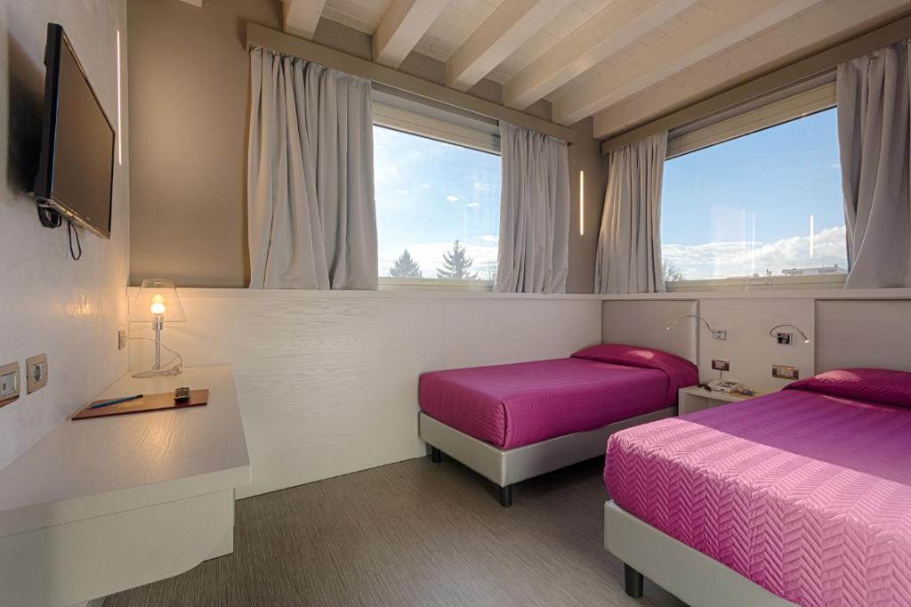 una camera con due letti, una TV e finestre di Hotel Doge a Vicenza
