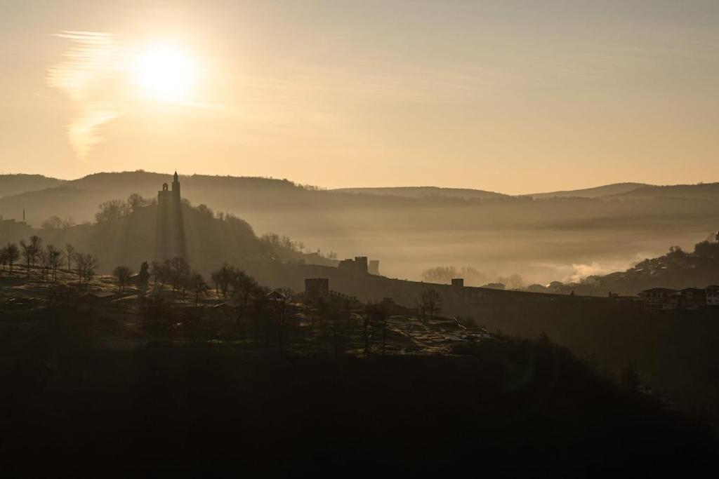 a misty sunrise with the sun rising over a city at House 46 in Veliko Tŭrnovo