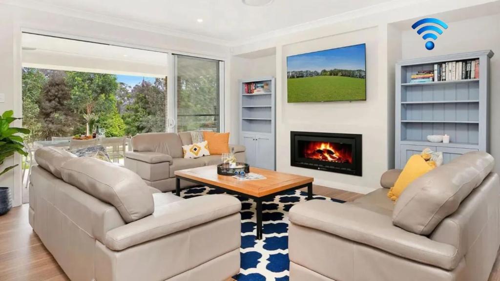 a living room with two couches and a fireplace at Forest Brae in Bundanoon