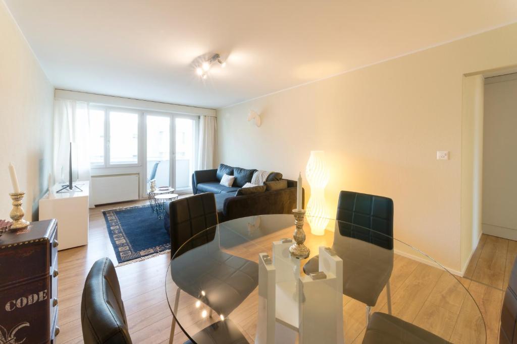 a living room with a glass table and chairs at RELOC Serviced Apartments Wallisellen Bhf. in Wallisellen