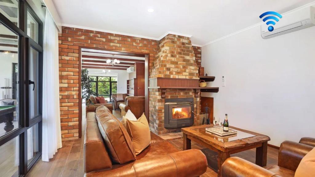 ein Wohnzimmer mit Sofa und Kamin in der Unterkunft Goolara in Burrawang