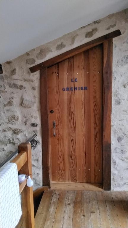 a wooden door in a room with a stone wall at Le grenier in Bazas