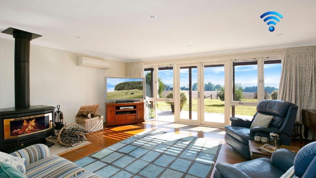 a living room with a fireplace and a tv at Warrington Park in Berrima