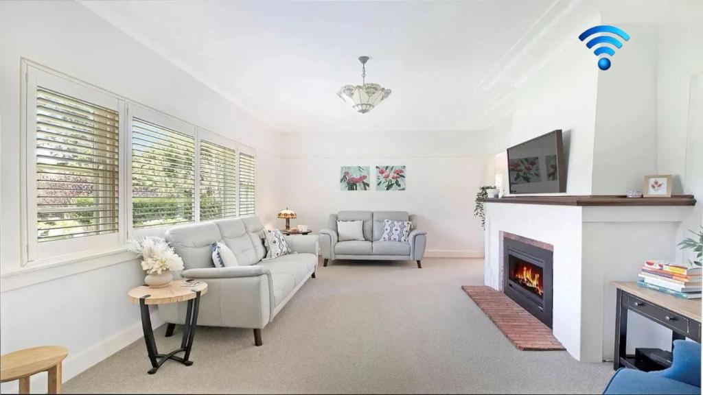 a living room with a couch and a fireplace at Kookaburra Cottage in Bowral